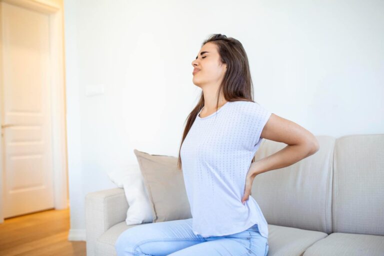 imagem de mulher sentada no sofá com dor nas costas