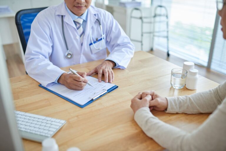 imagem de médico com paciente sentados em uma mesa preenchendo formulário de autorização do plano de saúde