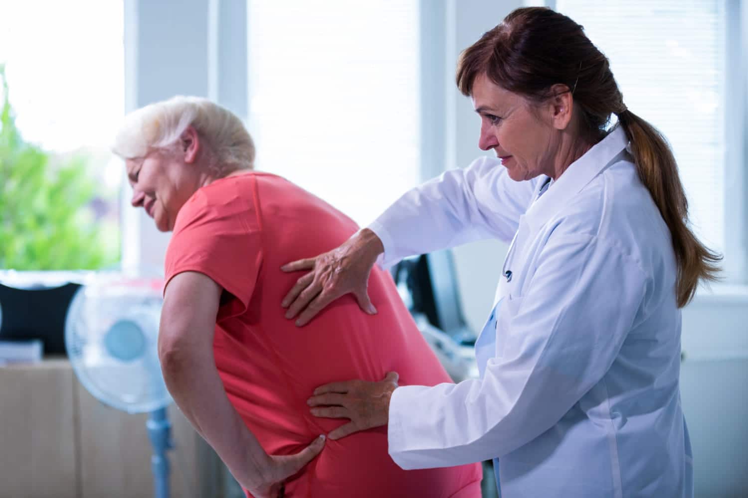 imagem de médica fazendo diagnóstico nas costas de uma paciente idosa com dor nas costas